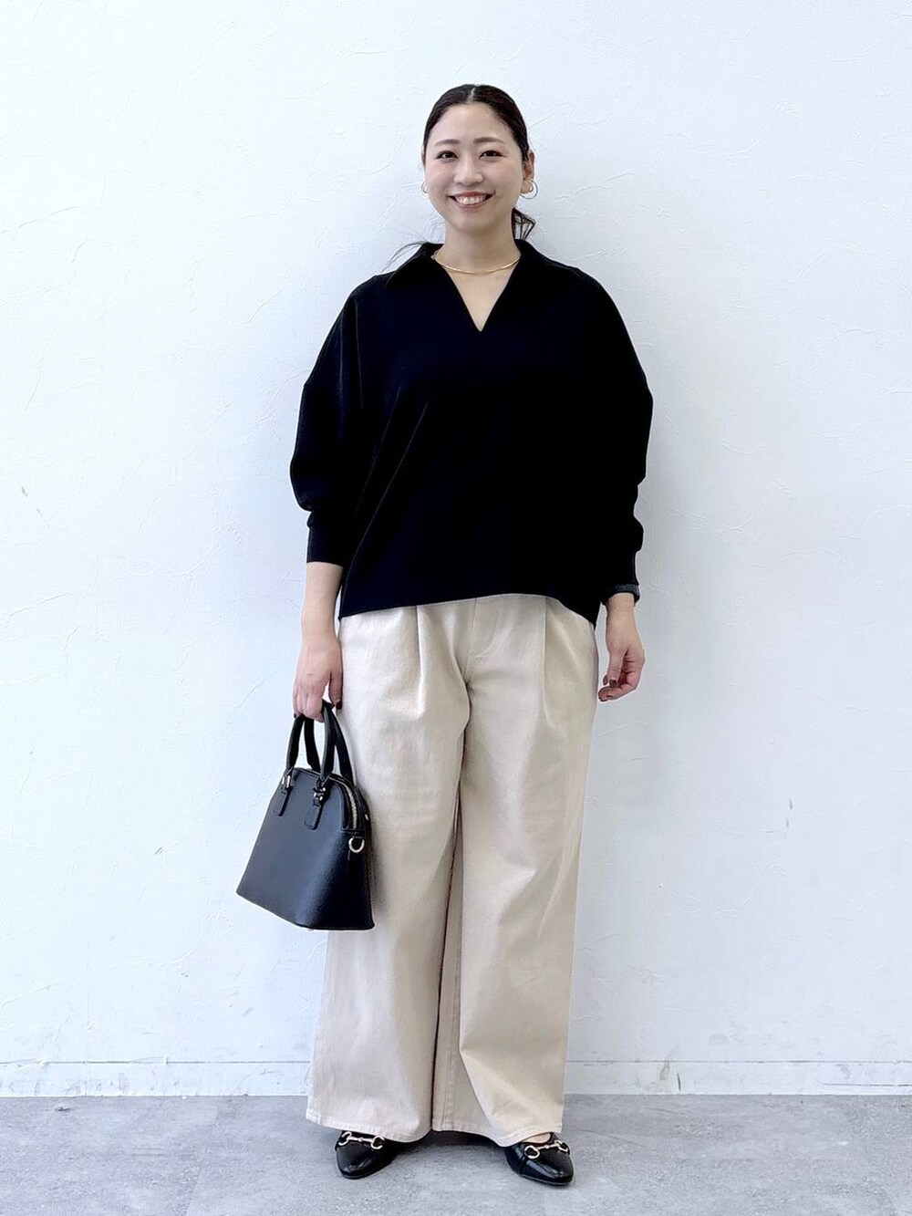 ブラック系のハンドバッグ、ベージュ系のデニムパンツ、ブラック系のパンプスを着用したレディースの冬コーディネートの2枚目の写真