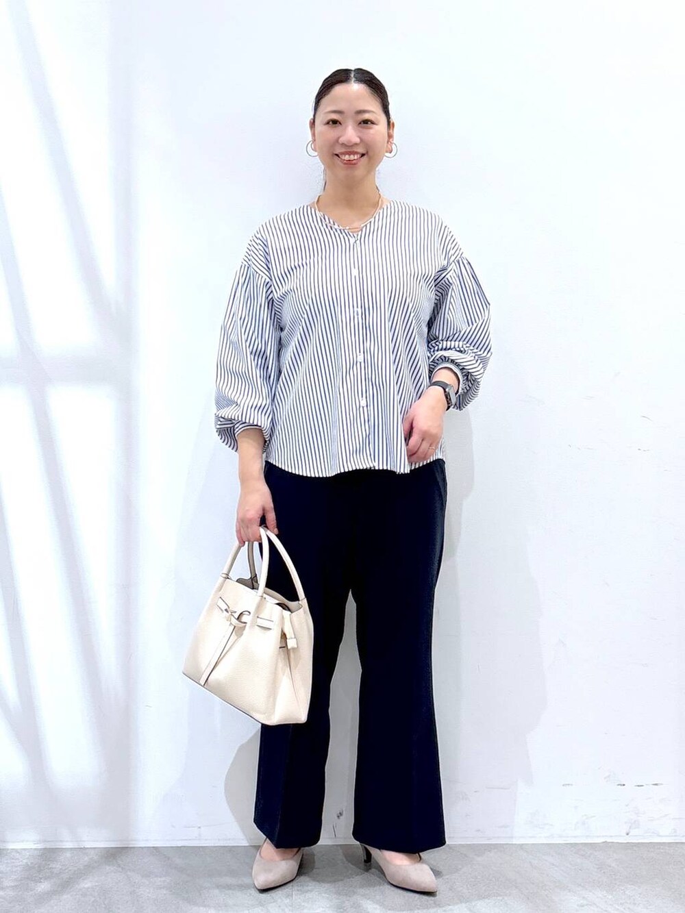 ブルー系のその他パンツ、ベージュ系のパンプス、ホワイト系のハンドバッグを着用したレディースの春コーディネートの2枚目の写真