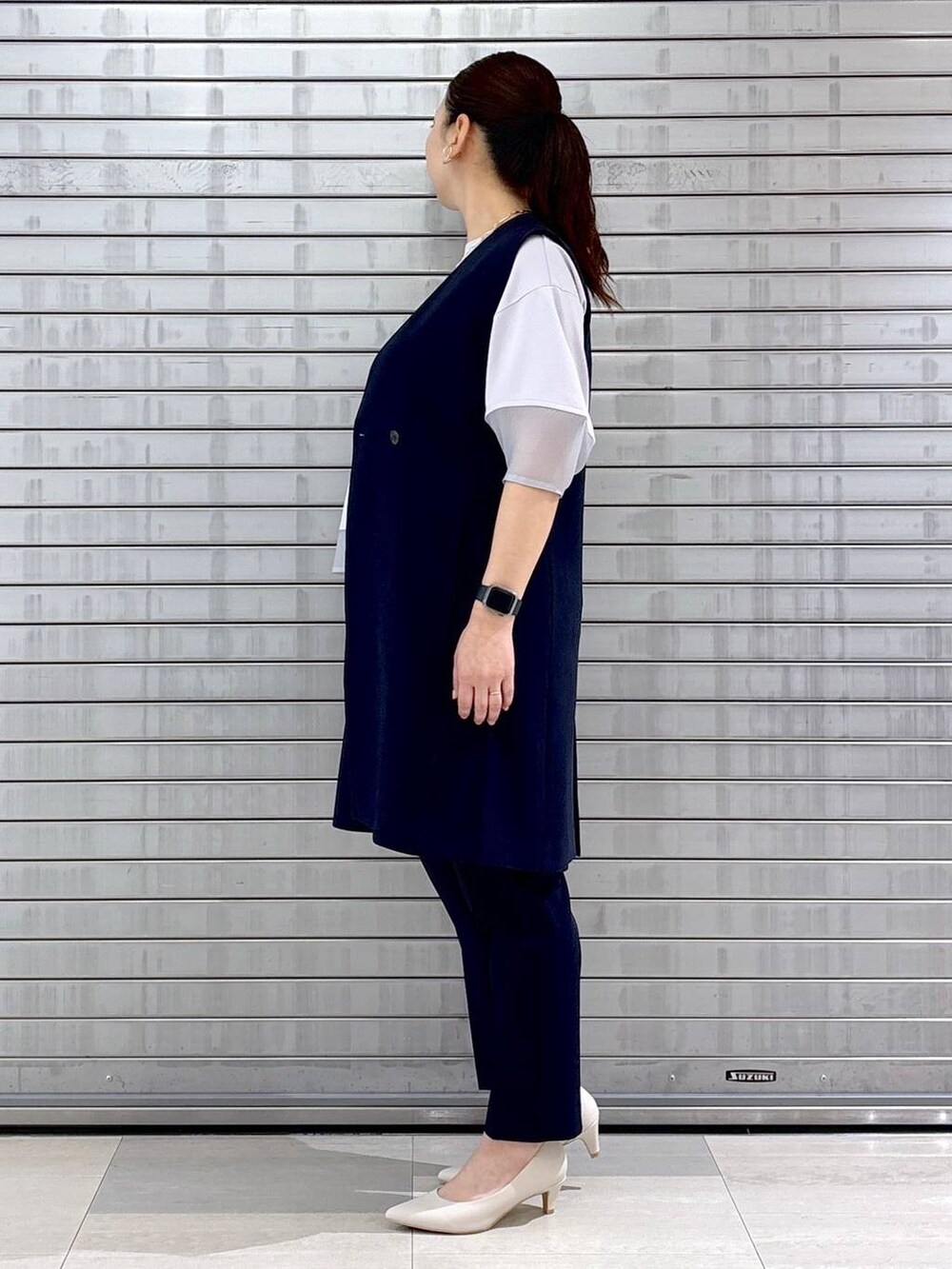 ホワイト系のパンプス、ベージュ系のハンドバッグ、ブルー系のその他パンツを着用したレディースの春コーディネートの3枚目の写真