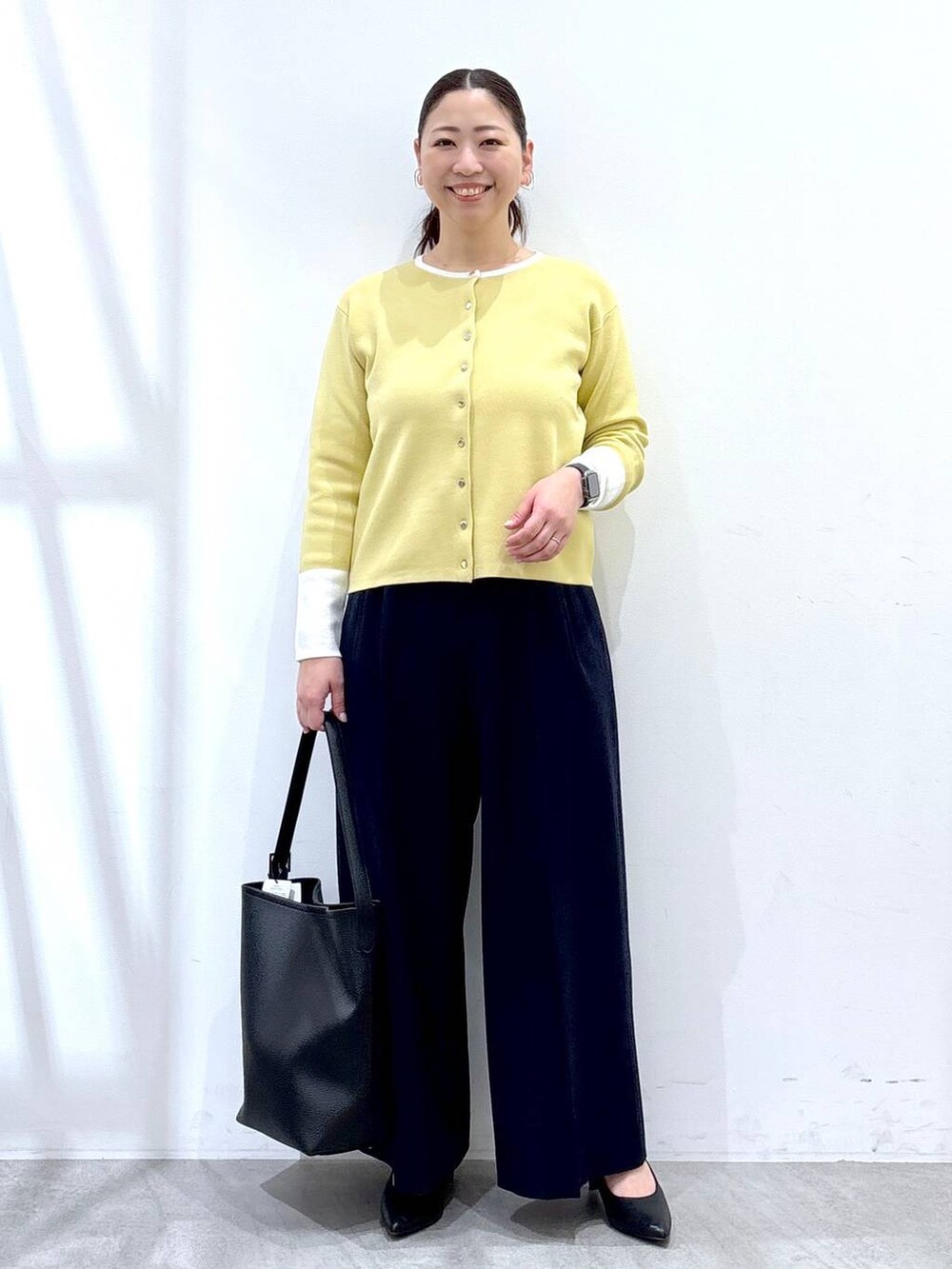 ブラック系のハンドバッグ、ブルー系のその他パンツ、イエロー系のカーディガン/ボレロを着用したレディースの春コーディネートの2枚目の写真