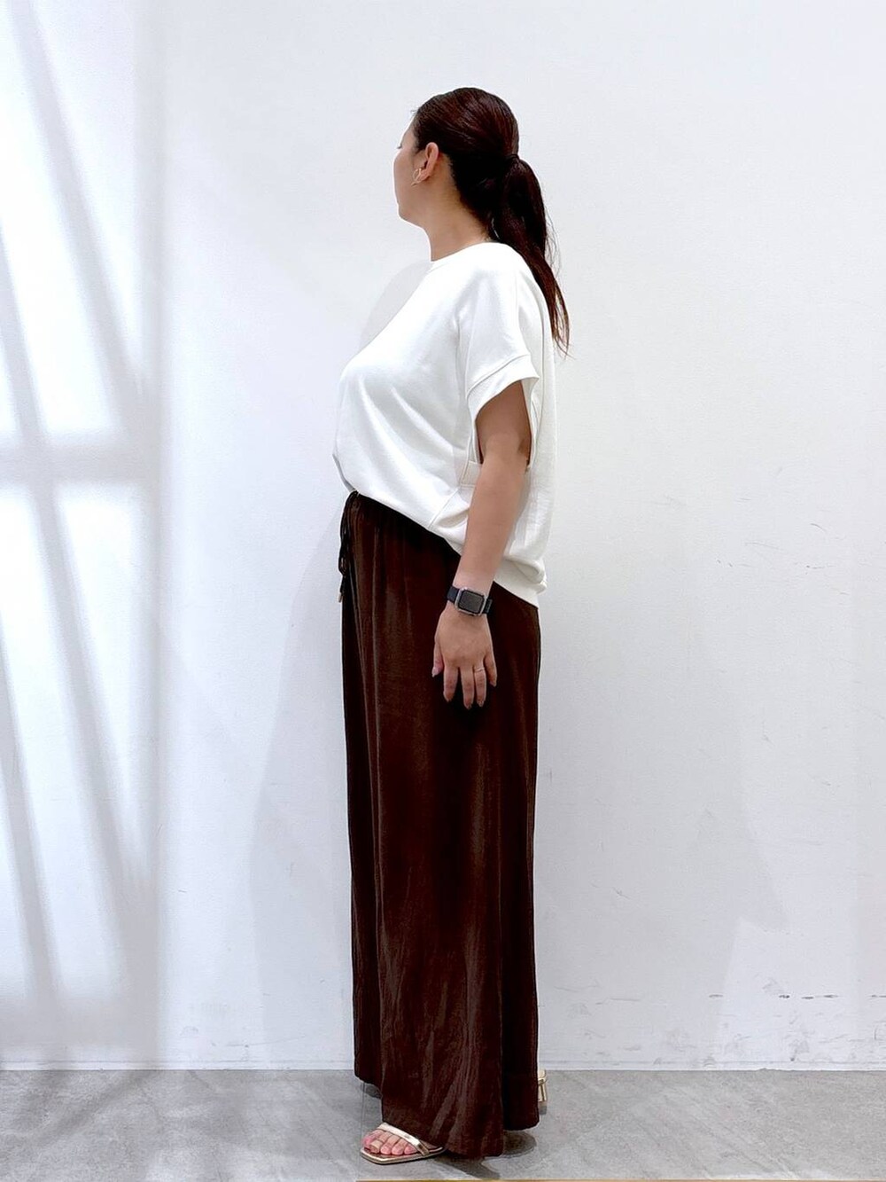 ブラウン系のその他パンツ、ゴールド系のサンダル、ホワイト系のTシャツ/カットソーを着用したレディースの夏コーディネートの2枚目の写真