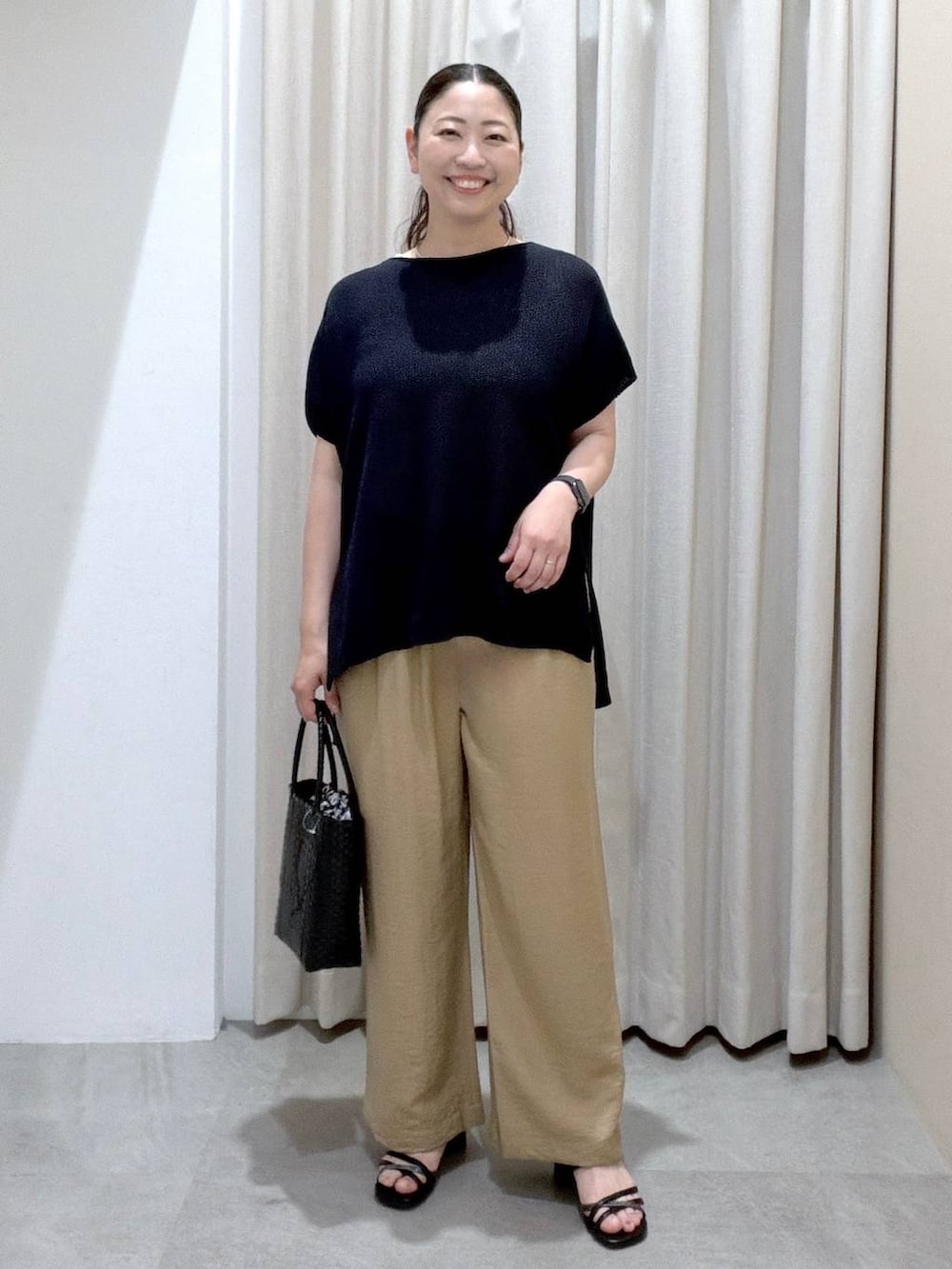 ブラック系のサンダル、ベージュ系のその他パンツ、ブラック系のかごバッグを着用したレディースの夏コーディネートの2枚目の写真