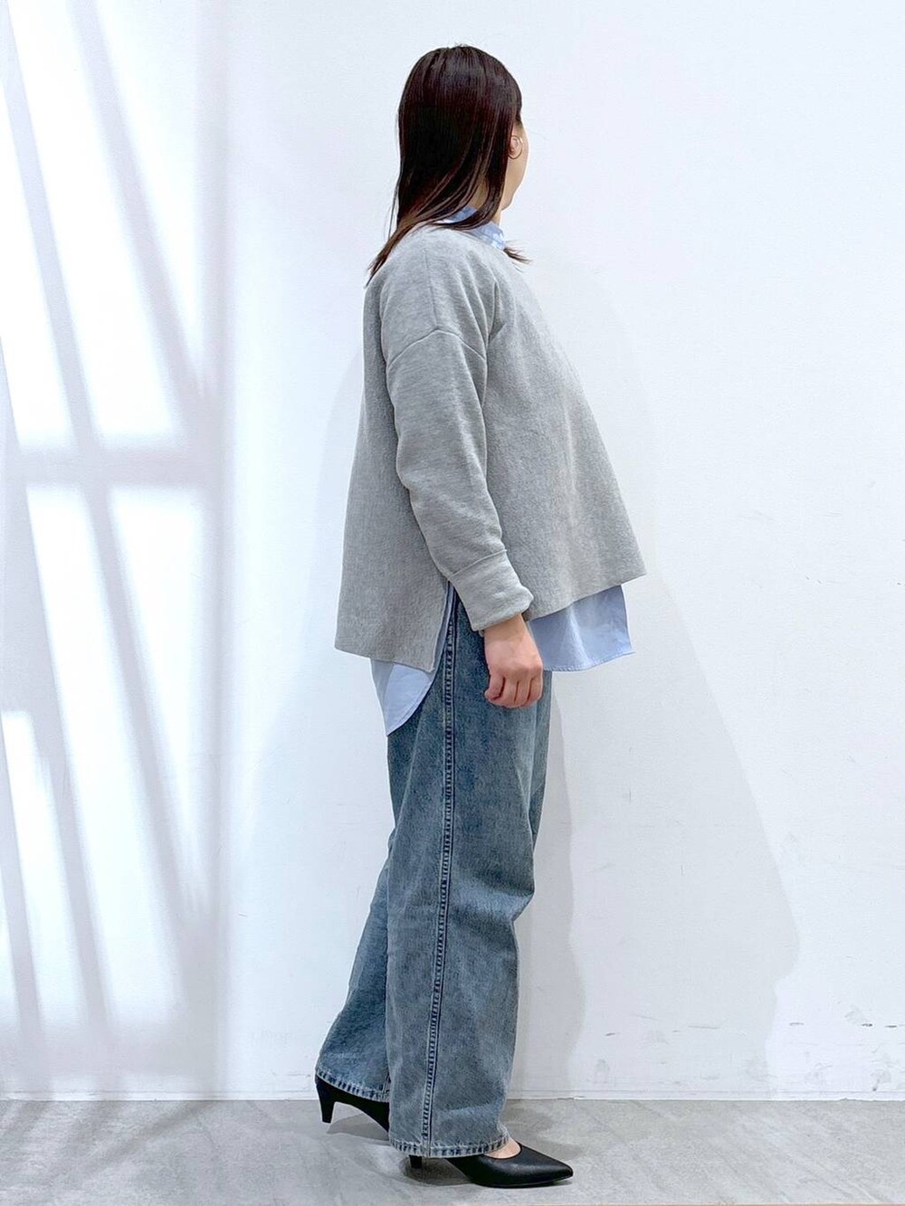 ブルー系のデニムパンツ、ブラック系のハンドバッグ、グレー系のニット/セーターを着用したレディースの冬コーディネートの5枚目の写真