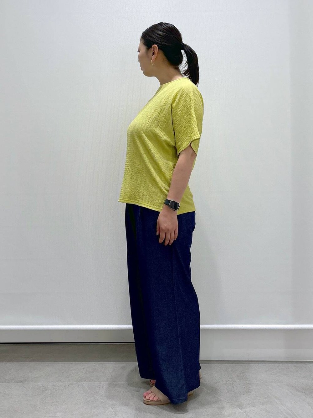 ホワイト系のトートバッグ、ベージュ系のサンダル、ブルー系のデニムパンツを着用したレディースの夏コーディネートの3枚目の写真