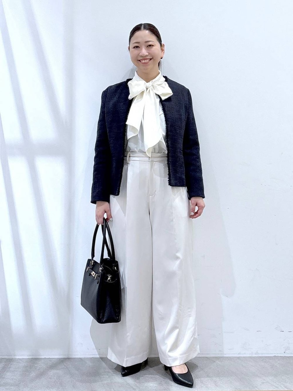 ブルー系のノーカラージャケット、ホワイト系のスラックス、ホワイト系のシャツ/ブラウスを着用したレディースの冬コーディネートの2枚目の写真