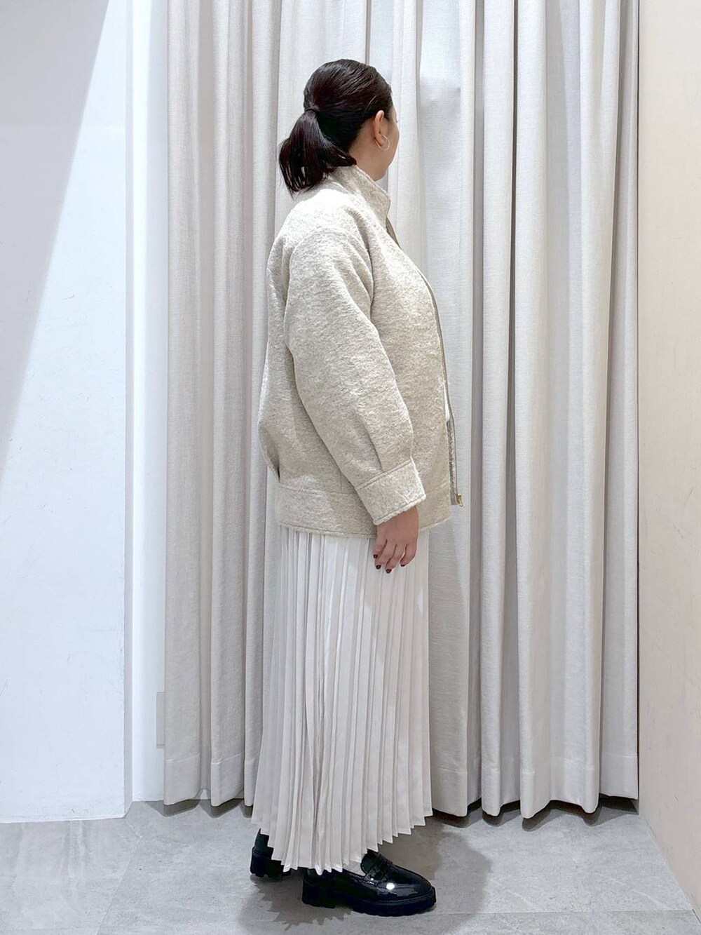 ブラック系のパンプス、ホワイト系のニット/セーター、ホワイト系のスカートを着用したレディースの秋コーディネートの5枚目の写真