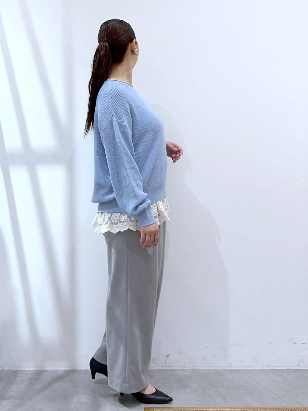 ブルー系のニット/セーター、ホワイト系のタンクトップ、ブラック系のハンドバッグを着用したレディースの春コーディネートの5枚目の写真