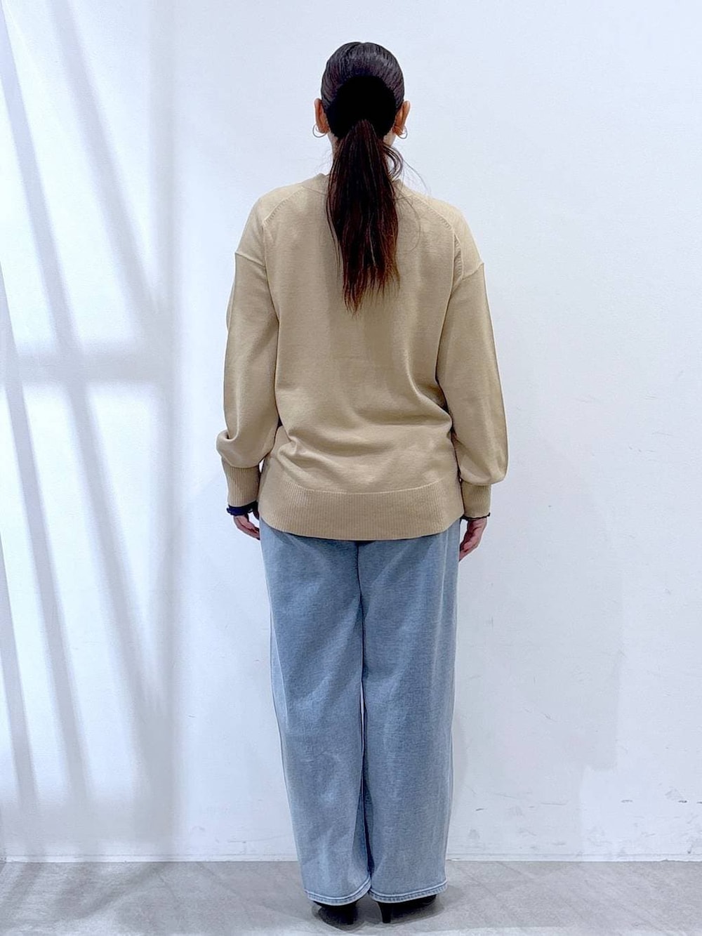 ブラック系のパンプス、ブルー系のデニムパンツ、ゴールド系のネックレスを着用したレディースの冬コーディネートの4枚目の写真