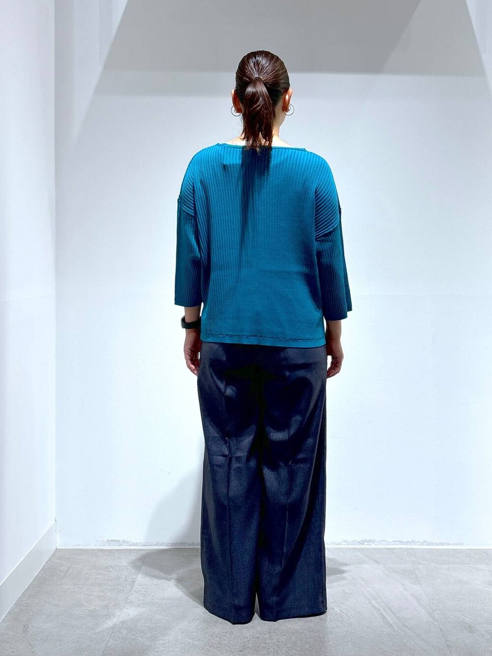 ブルー系のニット/セーター、ブラック系のパンプス、ブルー系のデニムパンツを着用したレディースの秋コーディネートの4枚目の写真