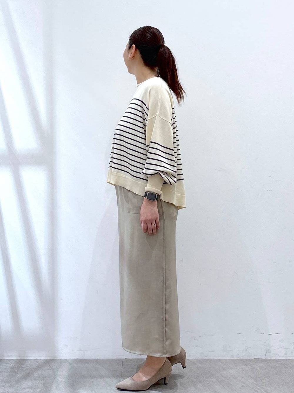 ベージュ系のパンプス、ホワイト系のスカート、ブルー系のニット/セーターを着用したレディースの春コーディネートの3枚目の写真