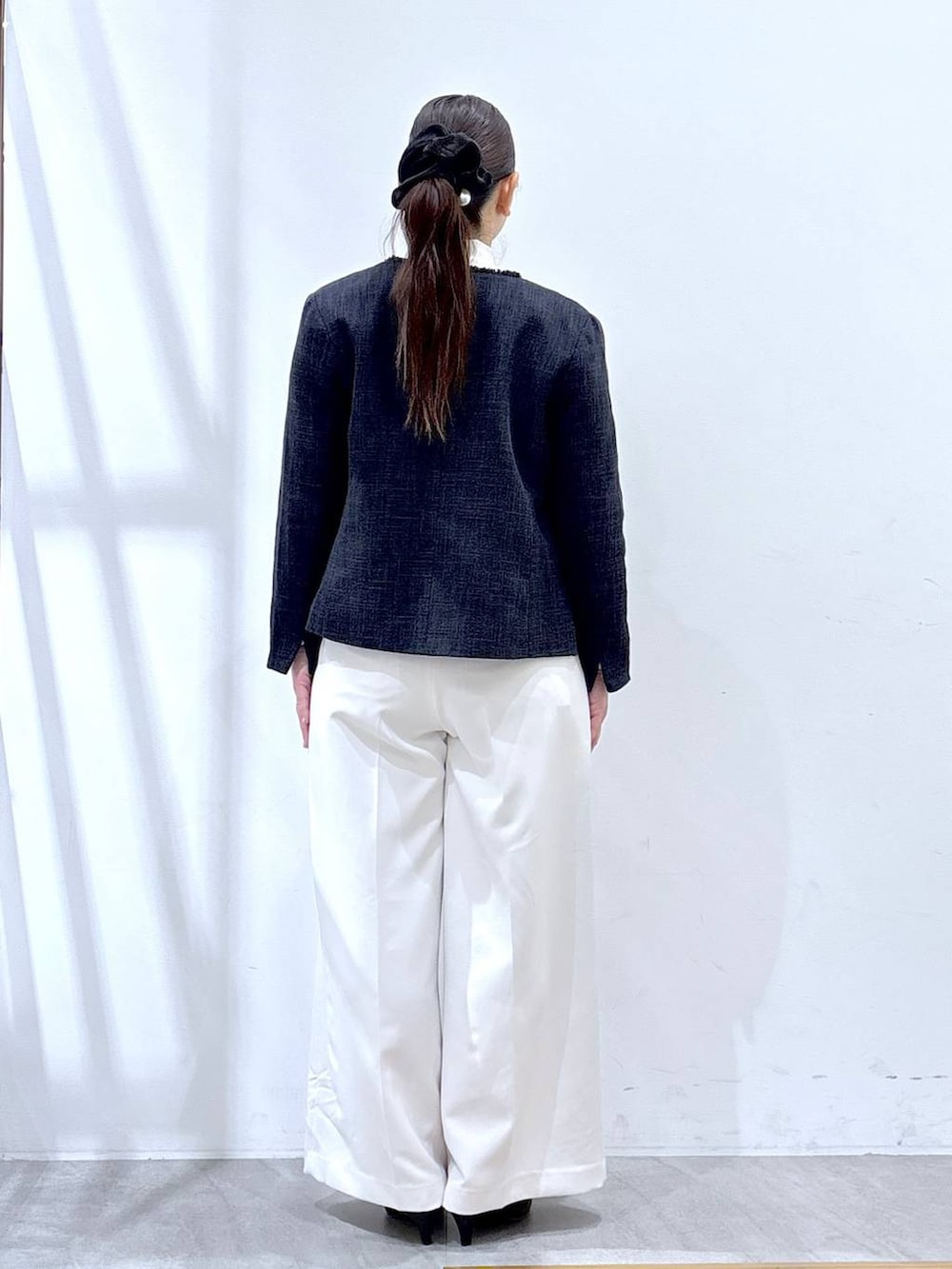 ブルー系のノーカラージャケット、ホワイト系のスラックス、ホワイト系のシャツ/ブラウスを着用したレディースの冬コーディネートの4枚目の写真