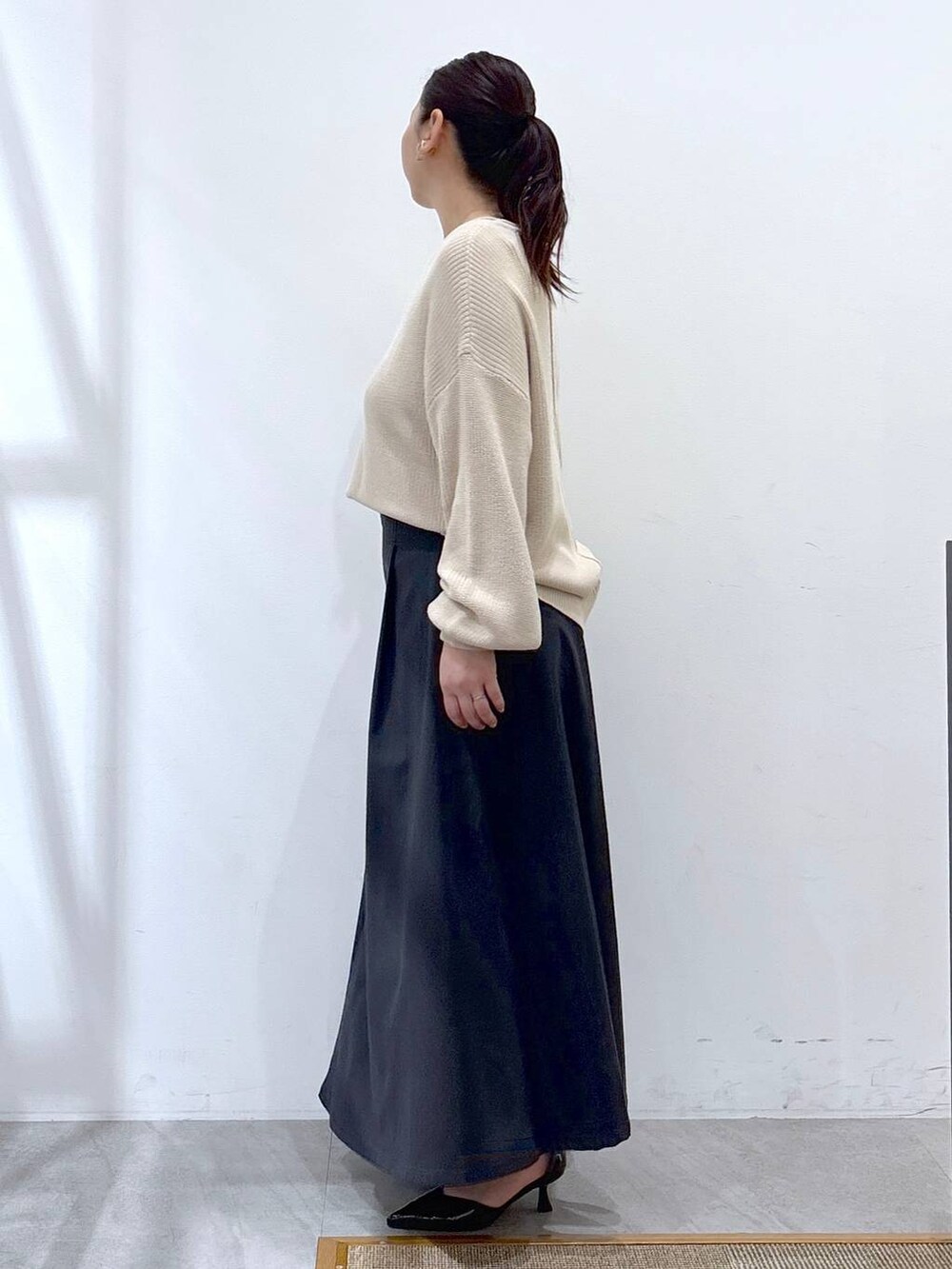 ホワイト系のニット/セーター、グレー系のスカートを着用したレディースの春コーディネートの3枚目の写真