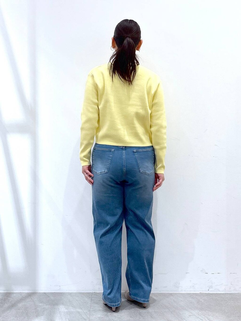 ベージュ系のパンプス、ブルー系のデニムパンツ、イエロー系のカーディガン/ボレロを着用したレディースの冬コーディネートの4枚目の写真