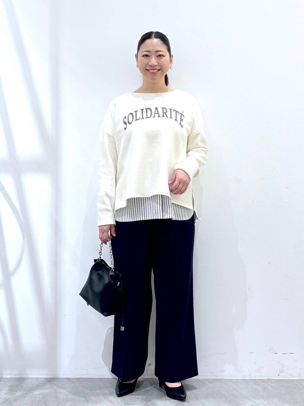 ホワイト系のニット/セーター、ブラック系のタンクトップ、ブルー系のその他パンツを着用したレディースの春コーディネートの2枚目の写真