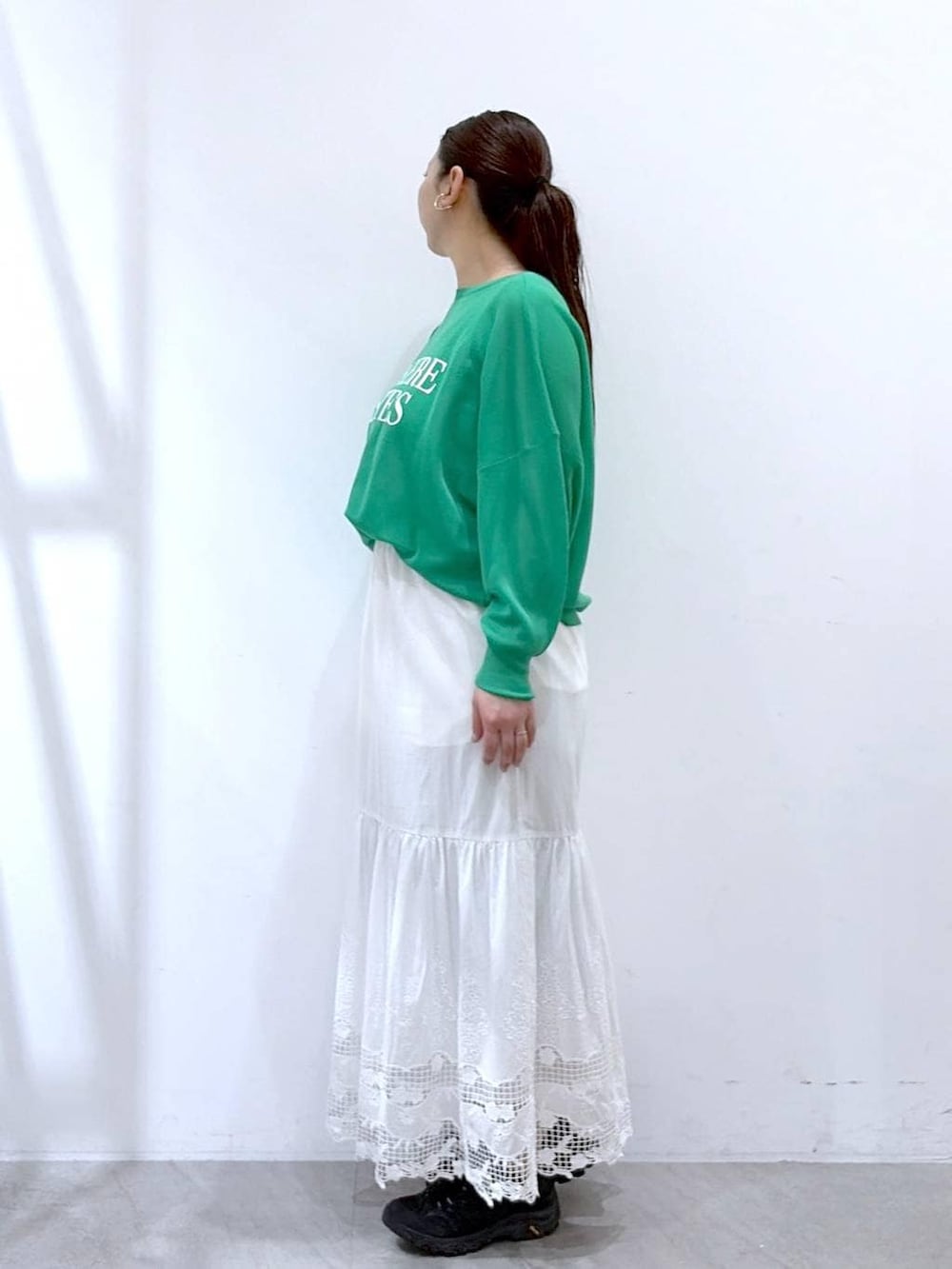 ブラック系のトートバッグ、ホワイト系のスカート、グリーン系のカーディガン/ボレロを着用したレディースの春コーディネートの3枚目の写真