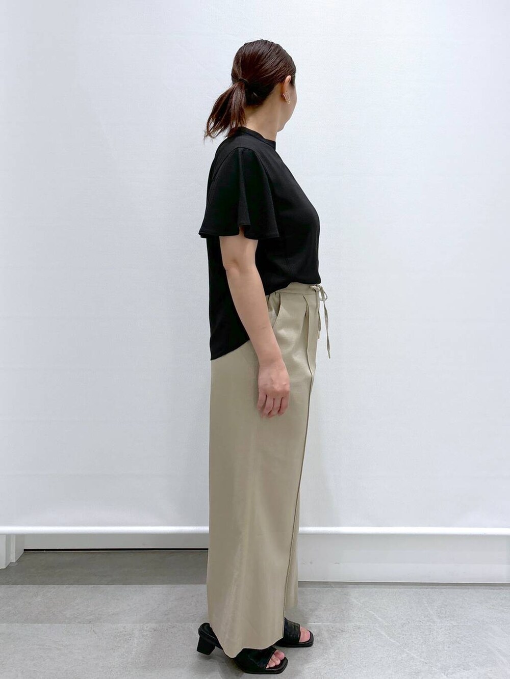 ベージュ系のその他パンツ、ブラック系のサンダル、ブラック系のシャツ/ブラウスを着用したレディースの春コーディネートの5枚目の写真