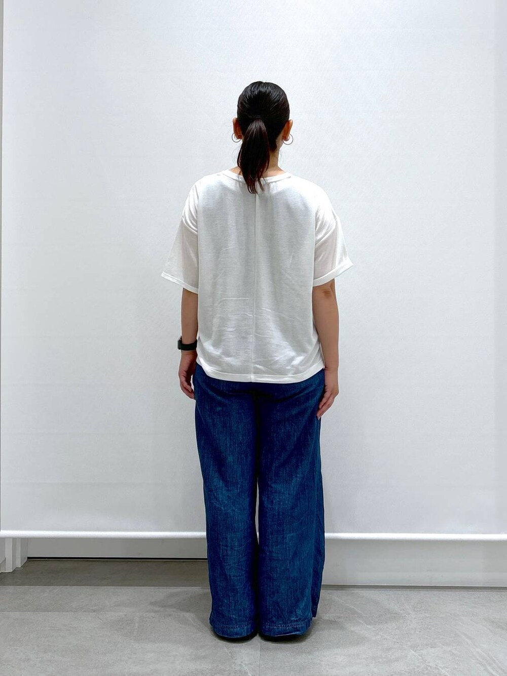 ブルー系のデニムパンツ、ブラック系のサンダル、ホワイト系のTシャツ/カットソーを着用したレディースの夏コーディネートの3枚目の写真