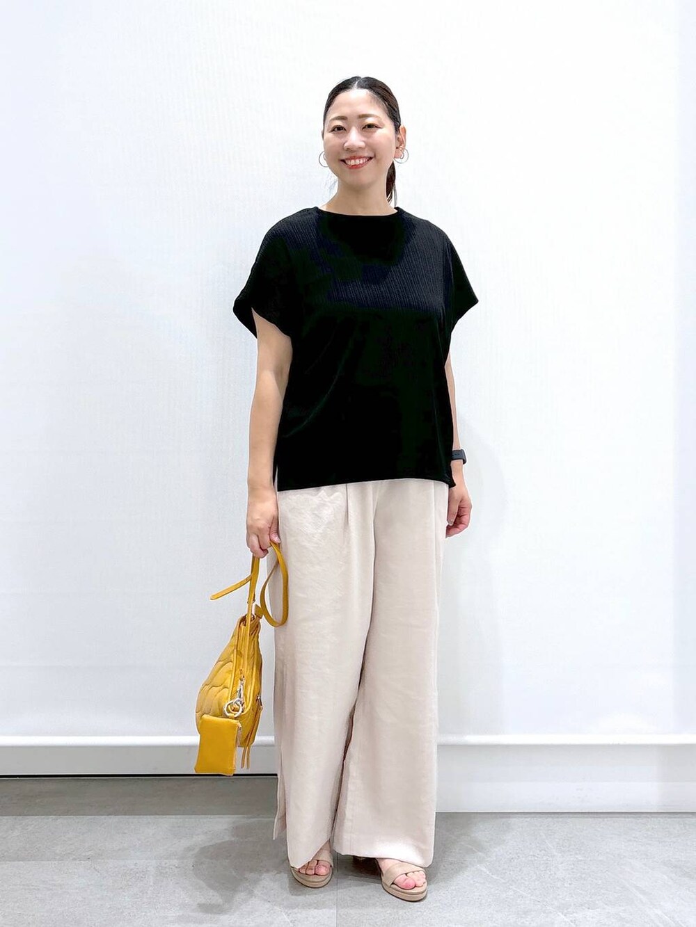 ベージュ系のその他パンツ、ブラック系のTシャツ/カットソー、ベージュ系のサンダルを着用したレディースの夏コーディネートの2枚目の写真