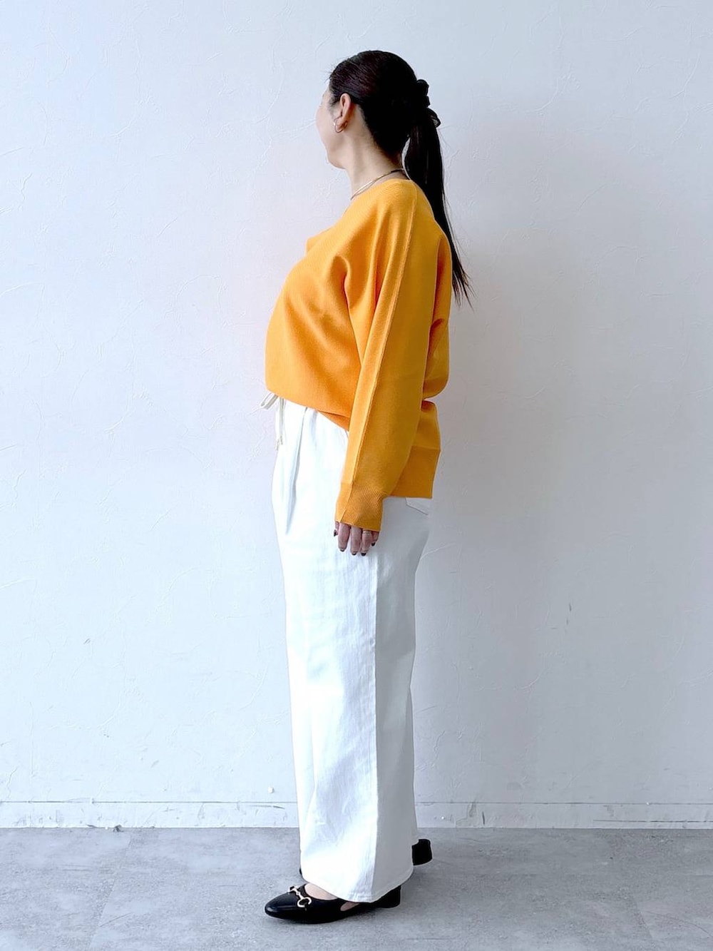 ホワイト系のデニムパンツ、ブラック系のパンプス、ブラック系のトートバッグを着用したレディースの春コーディネートの3枚目の写真