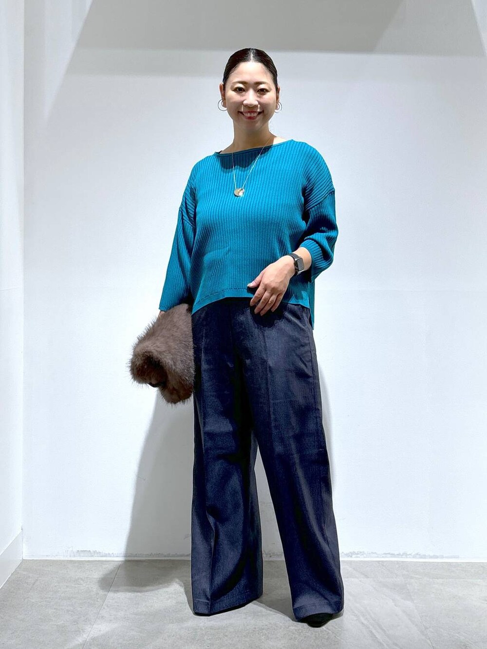 ブルー系のニット/セーター、ブラック系のパンプス、ブルー系のデニムパンツを着用したレディースの秋コーディネートの2枚目の写真