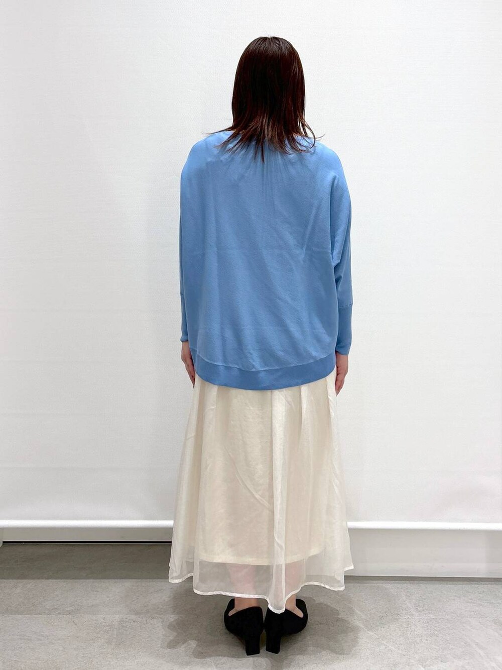 ホワイト系のスカート、ブラック系のショルダーバッグ、ブラック系のパンプスを着用したレディースの春コーディネートの4枚目の写真