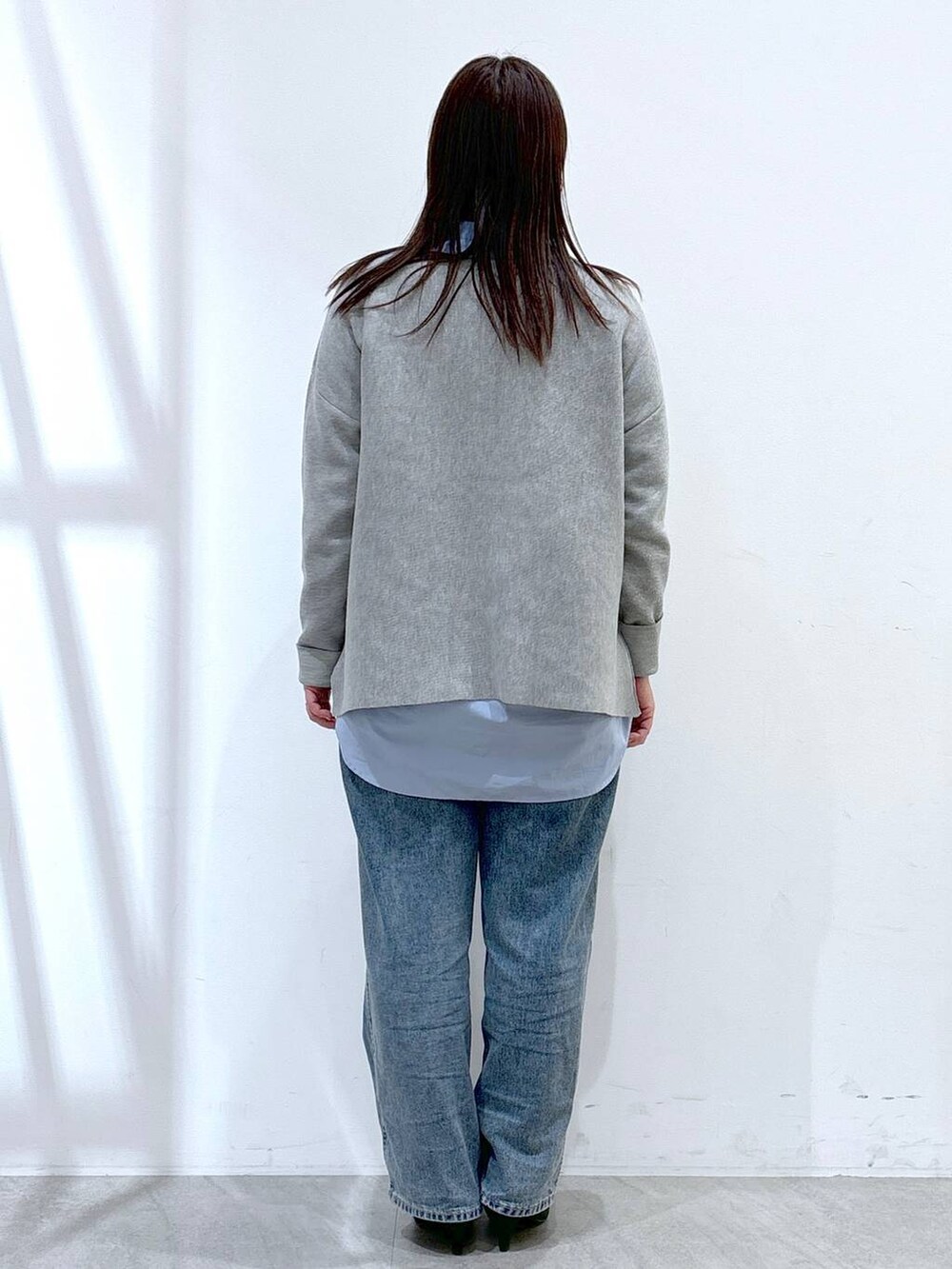 ブルー系のデニムパンツ、ブラック系のハンドバッグ、グレー系のニット/セーターを着用したレディースの冬コーディネートの4枚目の写真