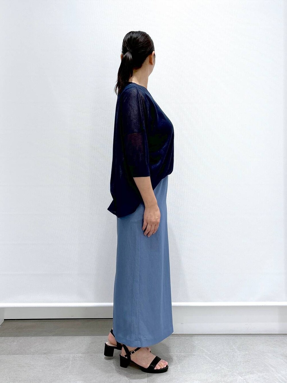 ブラック系のショルダーバッグ、ブラック系のサンダル、ブルー系のニット/セーターを着用したレディースの夏コーディネートの5枚目の写真