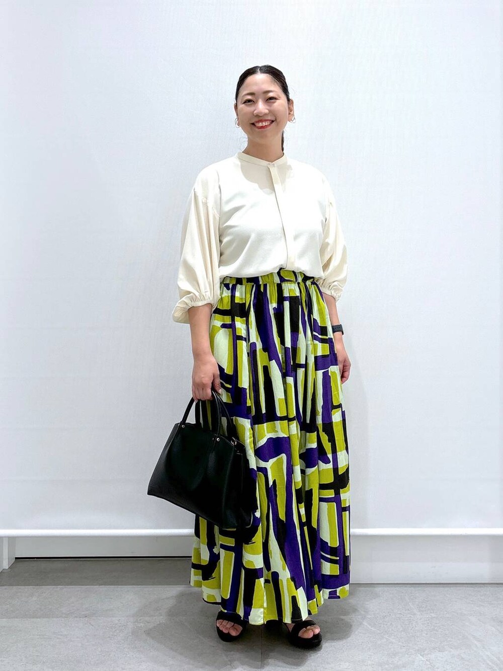 ブラック系のショルダーバッグ、ブラック系のサンダル、ホワイト系のシャツ/ブラウスを着用したレディースの夏コーディネートの2枚目の写真