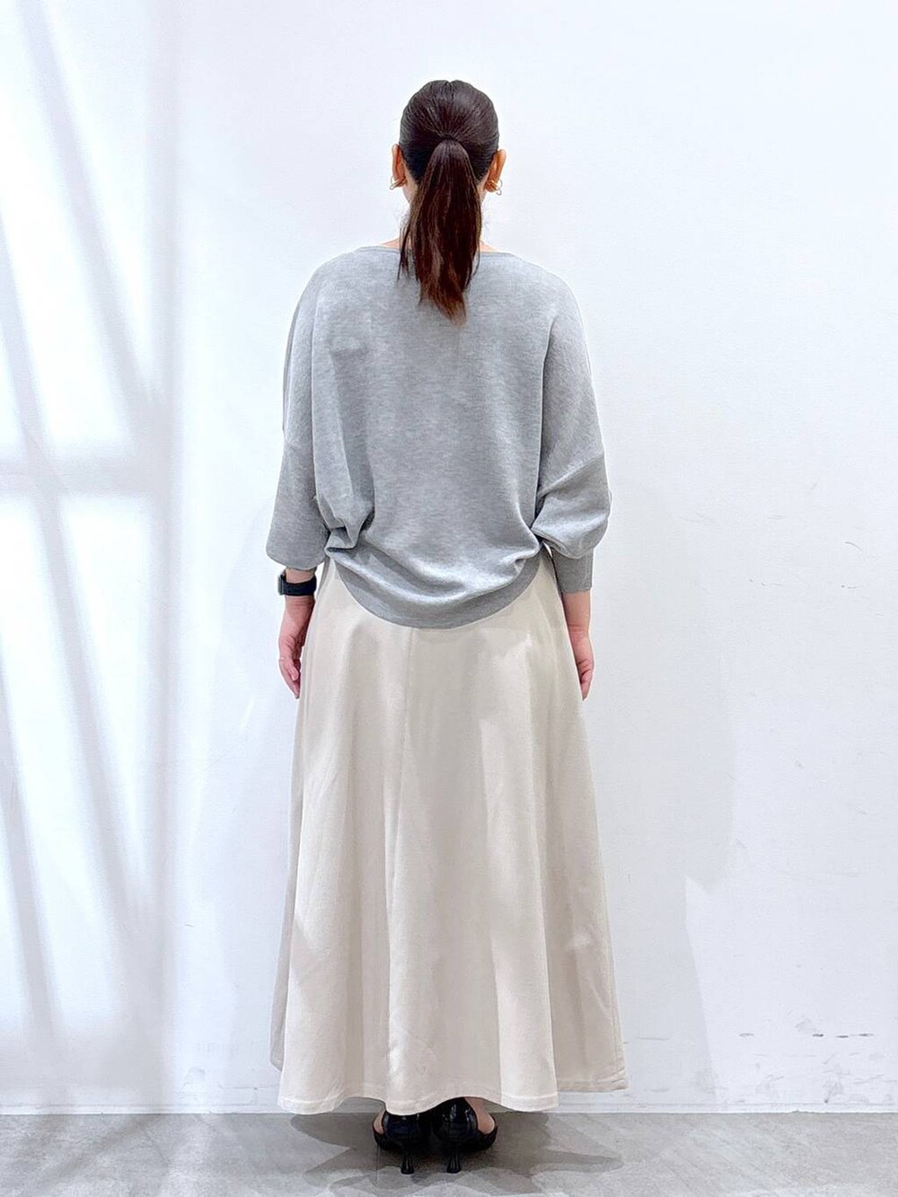 ブラック系のハンドバッグ、グレー系のニット/セーター、ベージュ系のスカートを着用したレディースの春コーディネートの4枚目の写真