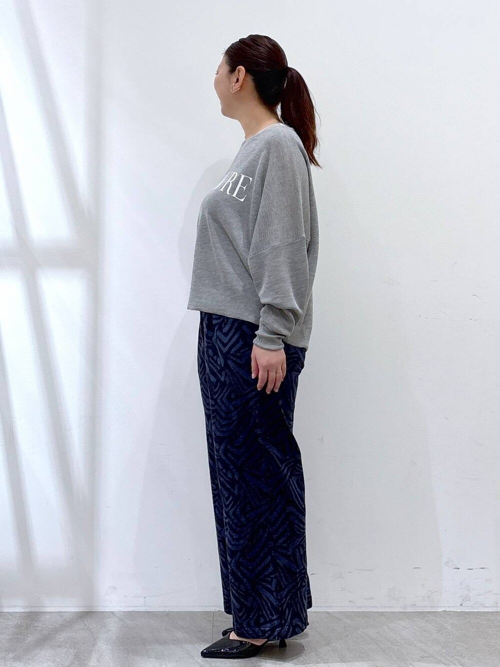 グレー系のニット/セーター、ブルー系のその他パンツ、ブラック系のハンドバッグを着用したレディースの春コーディネートの3枚目の写真