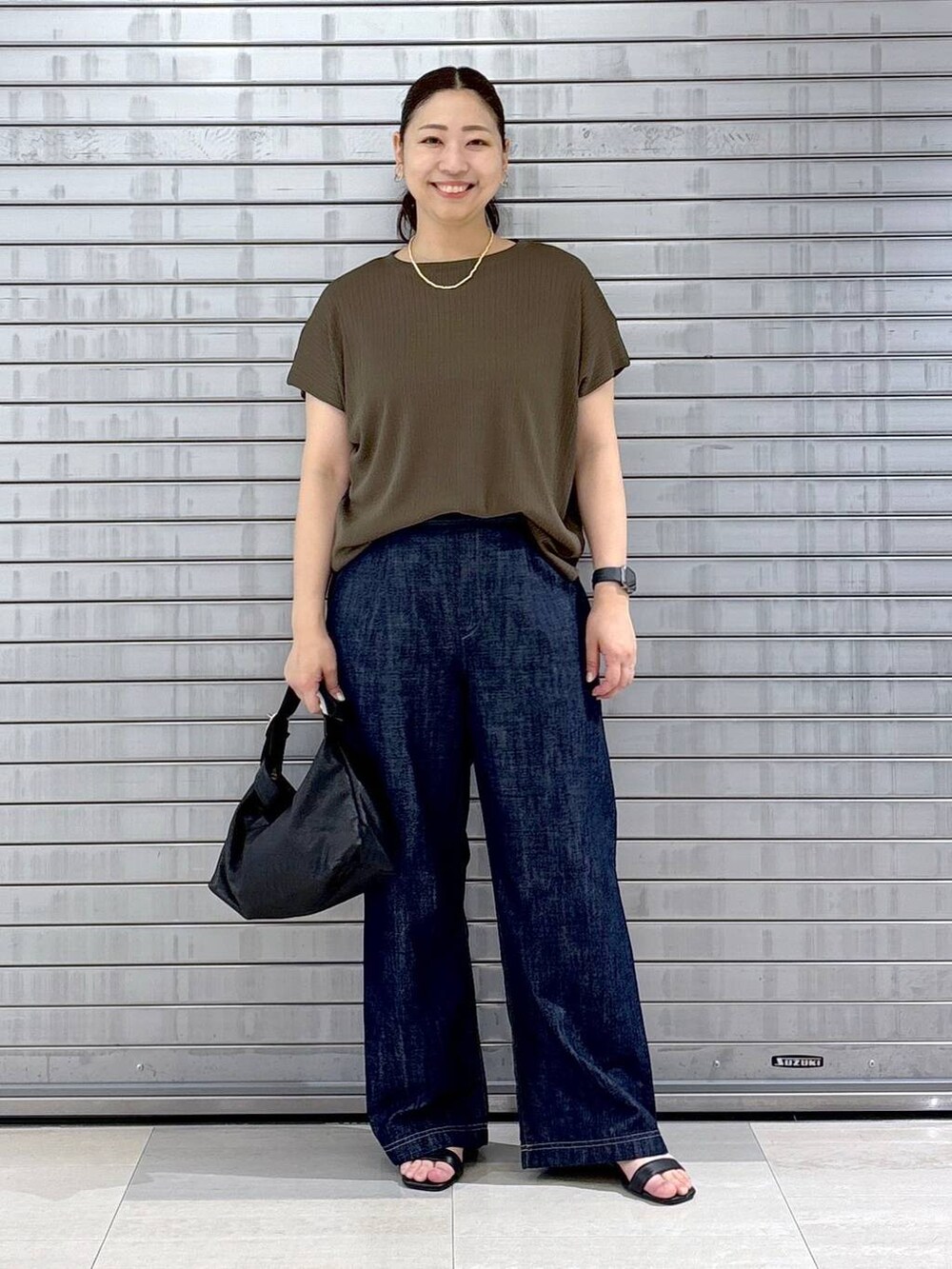 ブルー系のデニムパンツ、ブラック系のハンドバッグ、グリーン系のTシャツ/カットソーを着用したレディースの春コーディネートの2枚目の写真