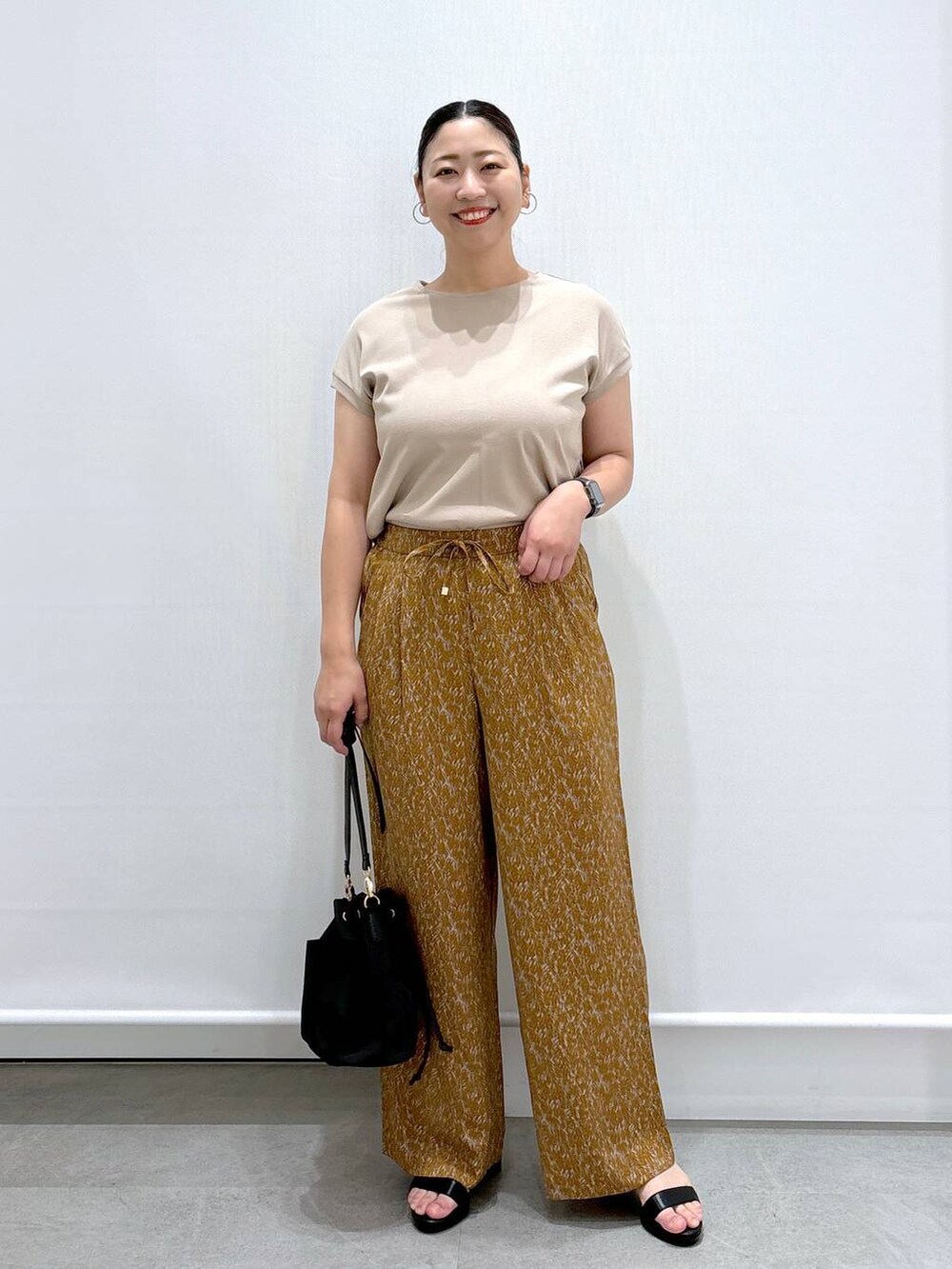 ベージュ系のTシャツ/カットソー、ブラック系のハンドバッグ、ブラウン系のその他パンツを着用したレディースの夏コーディネートの2枚目の写真