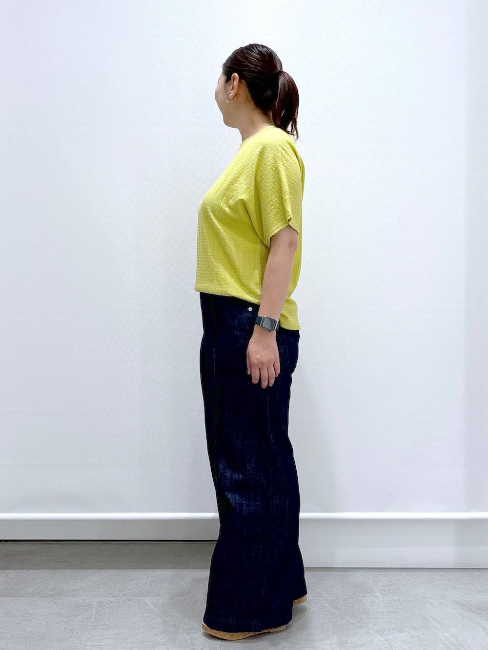 ブルー系のデニムパンツ、ベージュ系のサンダル、イエロー系のTシャツ/カットソーを着用したレディースの夏コーディネートの3枚目の写真