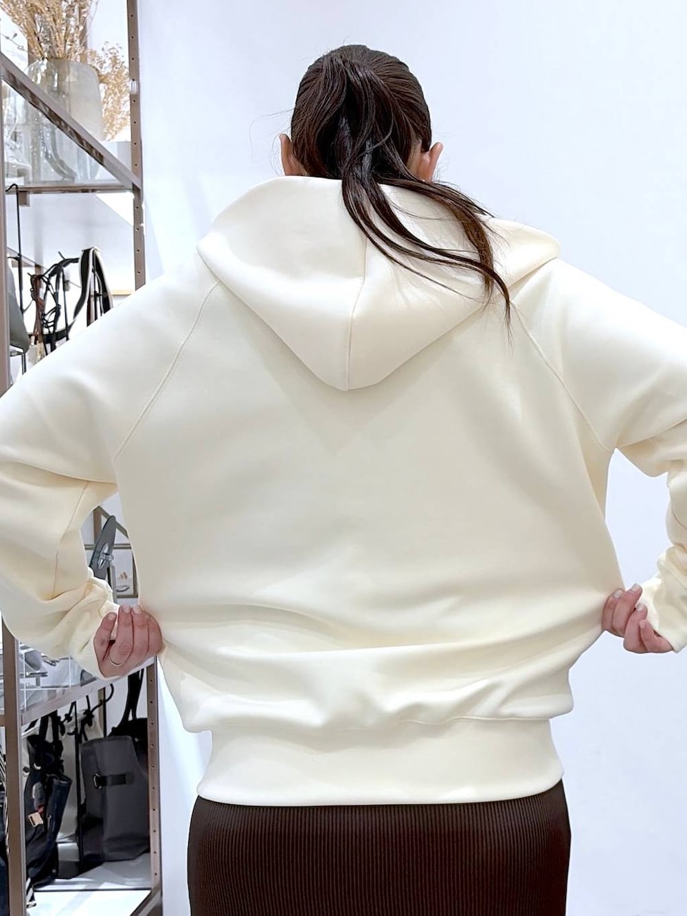 ホワイト系のパーカー、ブラウン系のスカート、ブラック系のショルダーバッグを着用したレディースの春コーディネートの9枚目の写真