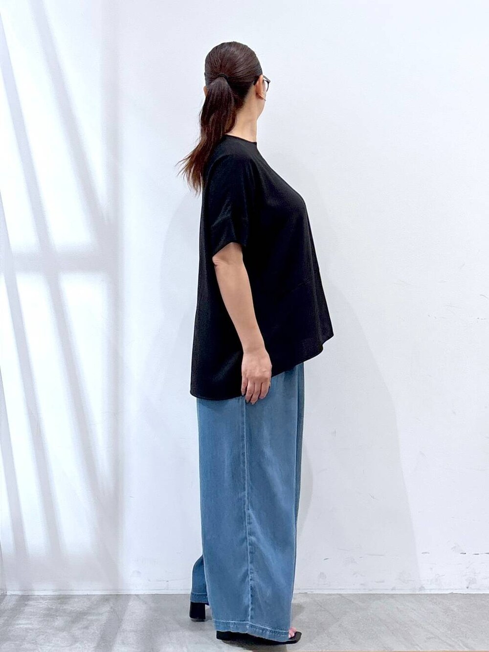 ブラック系のシャツ/ブラウス、ブラック系のサンダル、ブルー系のデニムパンツを着用したレディースの夏コーディネートの5枚目の写真