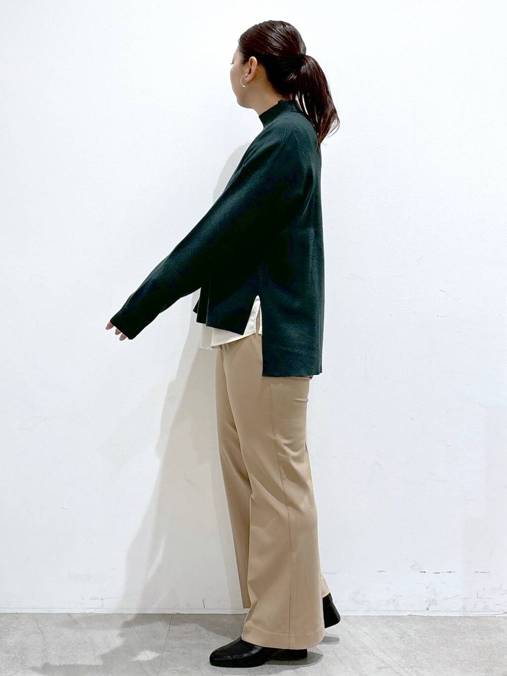 ホワイト系のシャツ/ブラウス、ブラック系のブーツ、グリーン系のニット/セーターを着用したレディースの秋コーディネートの3枚目の写真