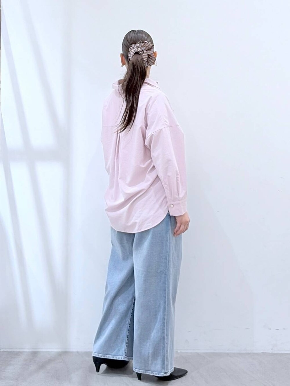 ブルー系のデニムパンツ、ピンク系のシャツ/ブラウス、ベージュ系のショルダーバッグを着用したレディースの春コーディネートの5枚目の写真