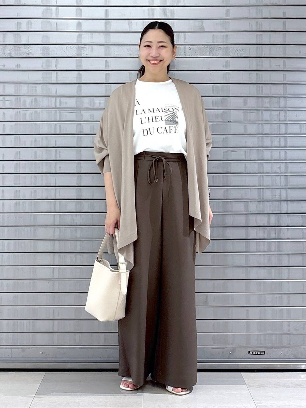 ベージュ系のハンドバッグ、ブラウン系のその他パンツ、ホワイト系のTシャツ/カットソーを着用したレディースの春コーディネートの2枚目の写真