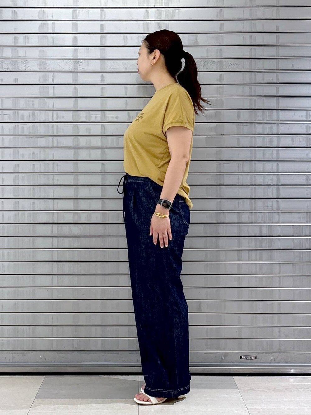 ブルー系のデニムパンツ、ホワイト系のハンドバッグ、イエロー系のTシャツ/カットソーを着用したレディースの春コーディネートの2枚目の写真