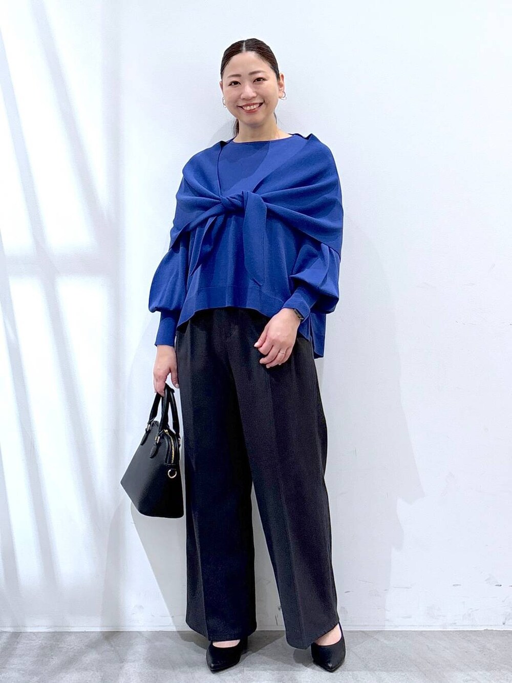 ブルー系のニット/セーター、グレー系のその他パンツ、ブルー系のストール/ショールを着用したレディースの春コーディネートの2枚目の写真
