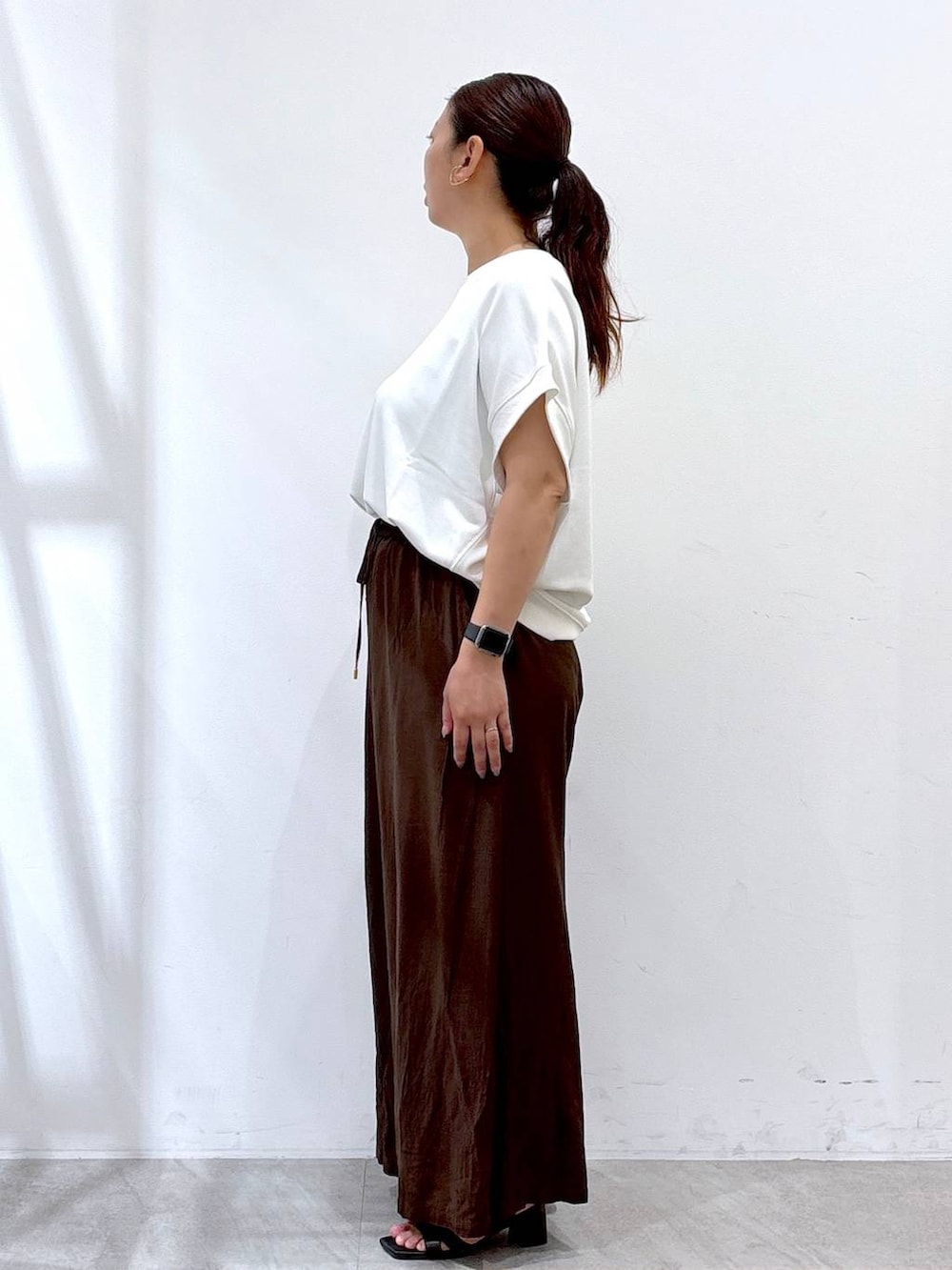 ブラウン系のその他パンツ、ブラック系のサンダル、ホワイト系のTシャツ/カットソーを着用したレディースの夏コーディネートの3枚目の写真