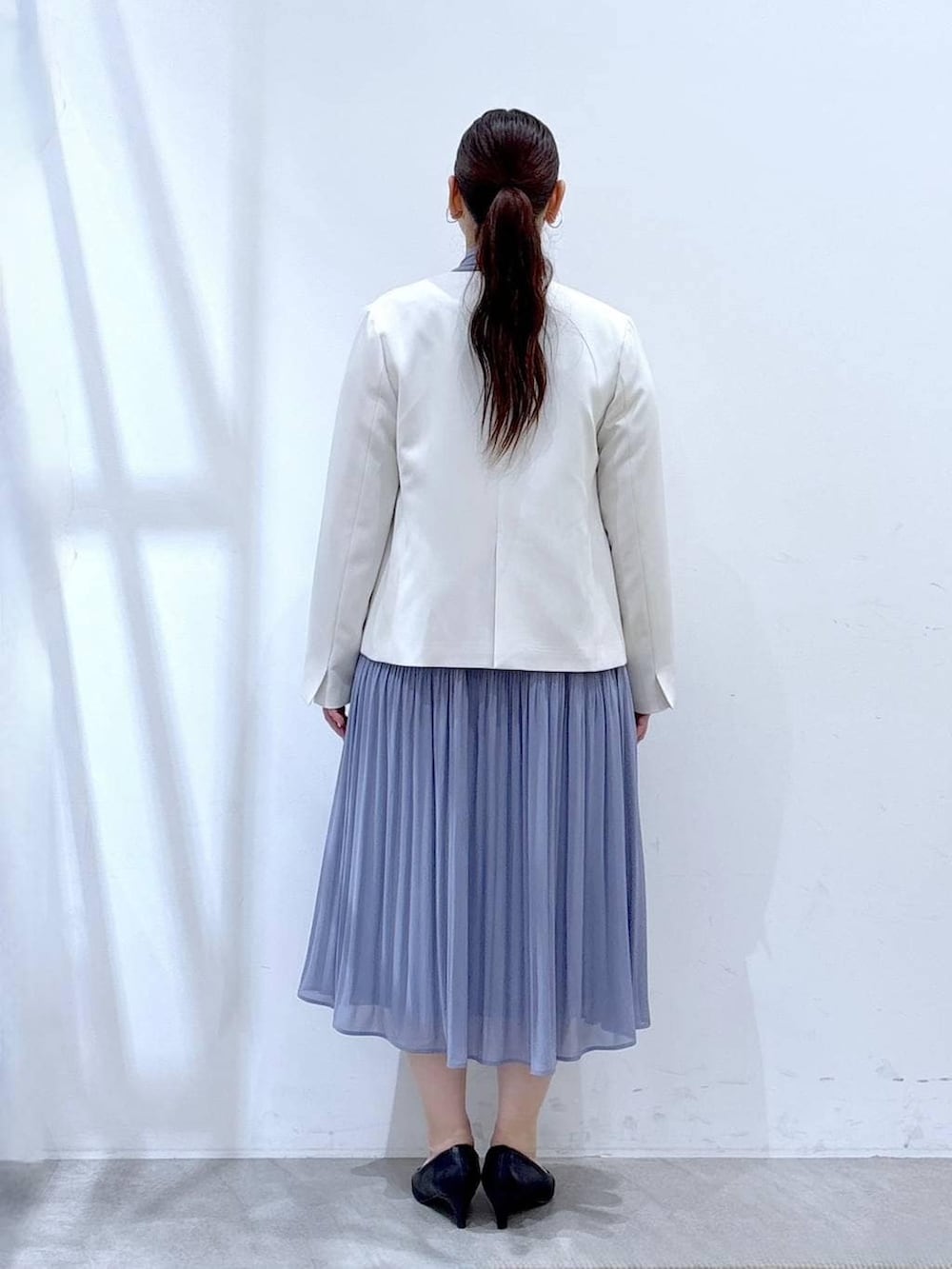 ブラック系のハンドバッグ、ホワイト系のノーカラージャケット、ブルー系のワンピースを着用したレディースの冬コーディネートの4枚目の写真