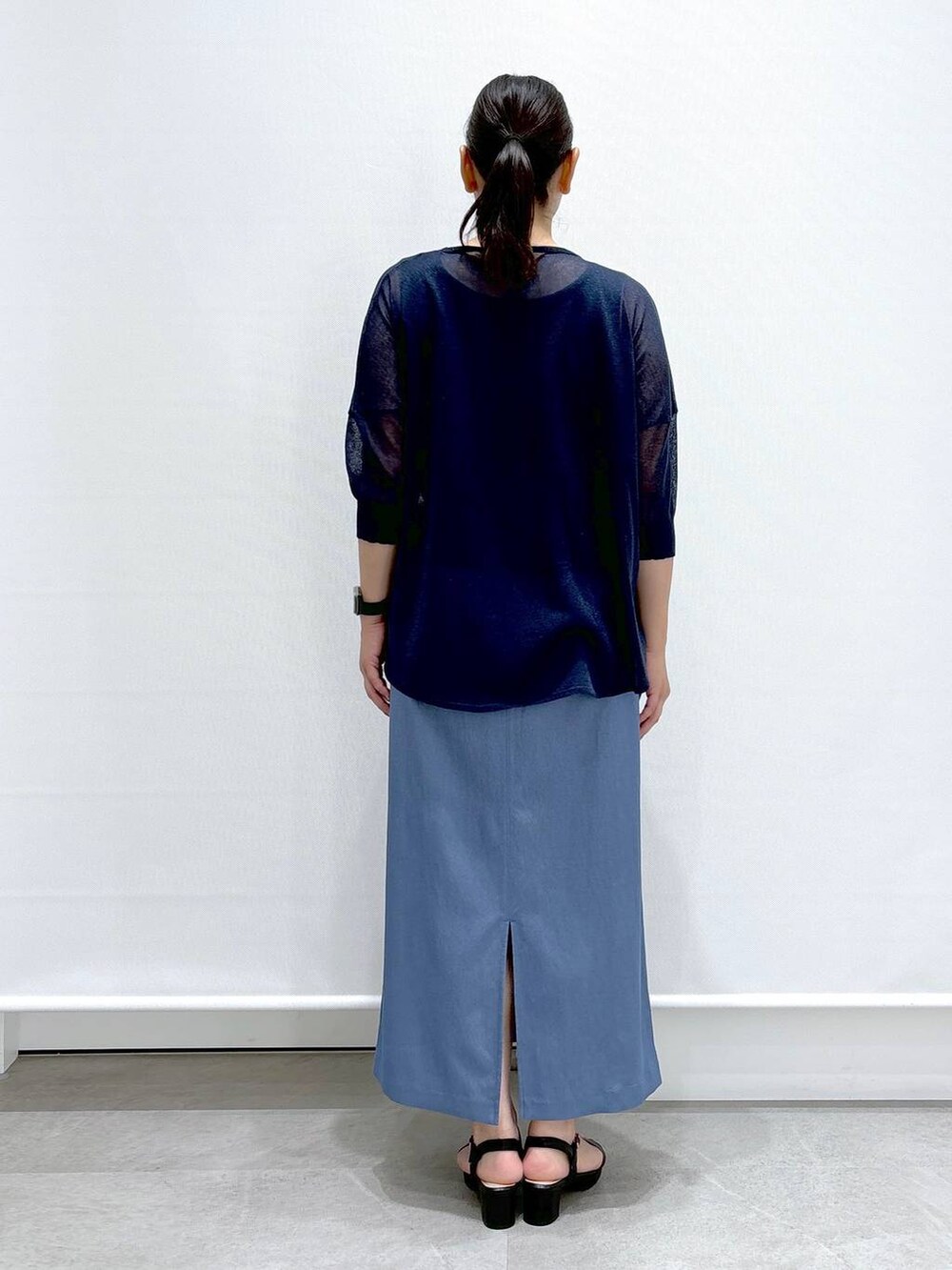 ブラック系のショルダーバッグ、ブラック系のサンダル、ブルー系のニット/セーターを着用したレディースの夏コーディネートの4枚目の写真