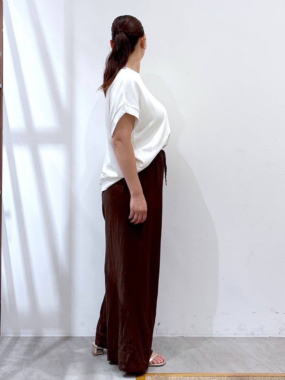 ブラウン系のその他パンツ、ゴールド系のサンダル、ホワイト系のTシャツ/カットソーを着用したレディースの夏コーディネートの4枚目の写真