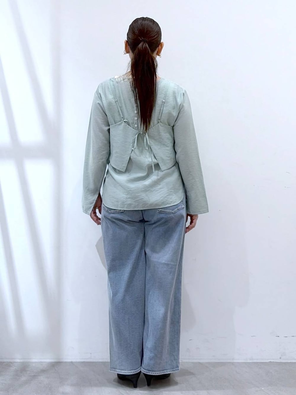 ブルー系のデニムパンツ、ブラック系のハンドバッグ、グリーン系のシャツ/ブラウスを着用したレディースの春コーディネートの4枚目の写真