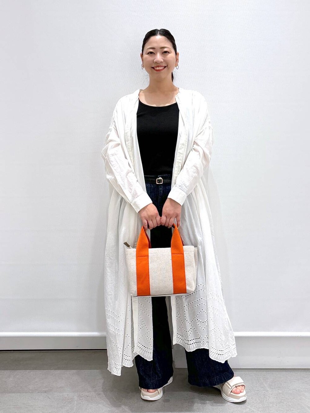 ブルー系のデニムパンツ、ブラック系のタンクトップ、ブルー系のデニムパンツを着用したレディースの夏コーディネートの2枚目の写真