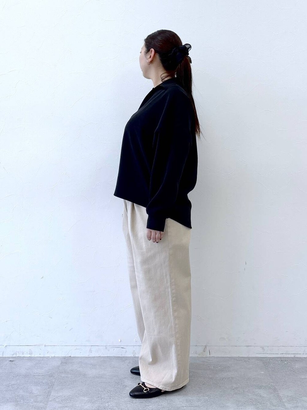 ブラック系のハンドバッグ、ベージュ系のデニムパンツ、ブラック系のパンプスを着用したレディースの冬コーディネートの3枚目の写真