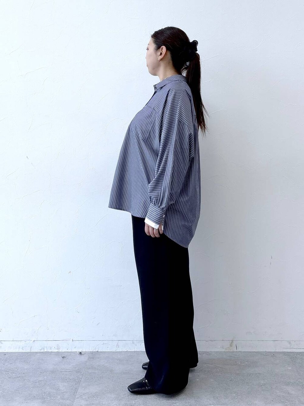 ブラック系のハンドバッグ、ブラック系のパンプス、ブルー系のシャツ/ブラウスを着用したレディースの冬コーディネートの3枚目の写真