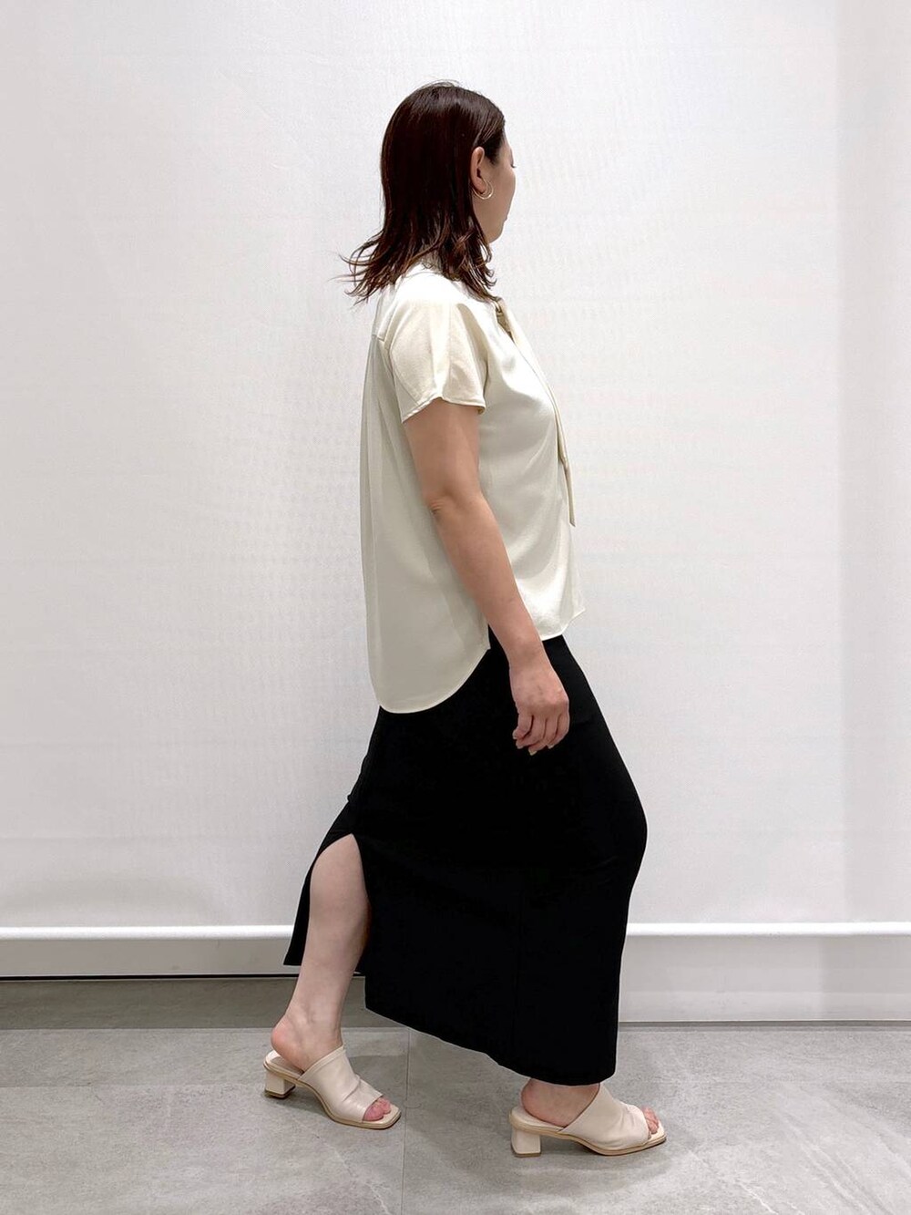 ホワイト系のシャツ/ブラウス、ホワイト系のサンダル、ブラック系のスカートを着用したレディースの夏コーディネートの6枚目の写真