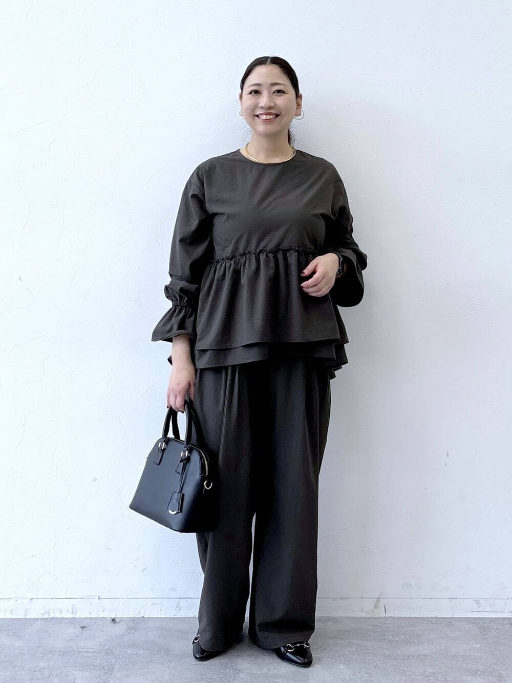 ブラック系のハンドバッグ、ブラック系のパンプス、ブラウン系のその他パンツを着用したレディースの冬コーディネートの2枚目の写真